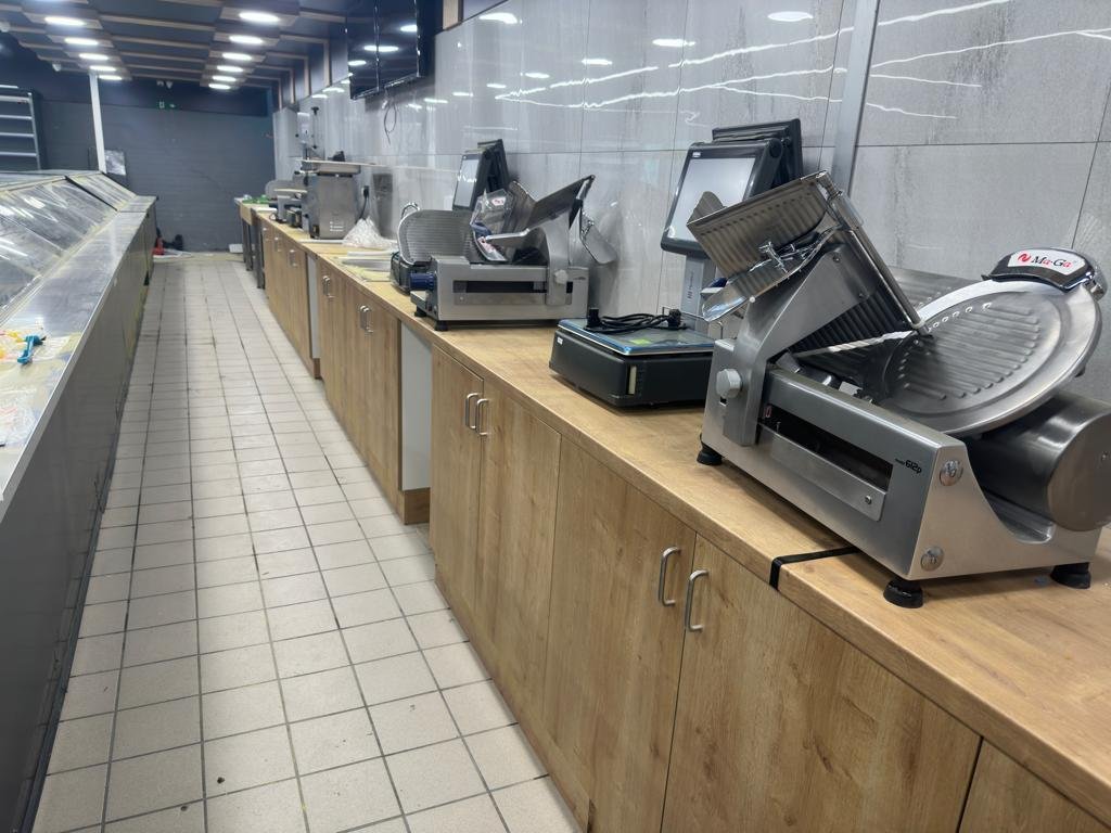 Butchery back counter with meat slicers and stainless steel equipment on custom wooden cabinets – DLG Shopfitting