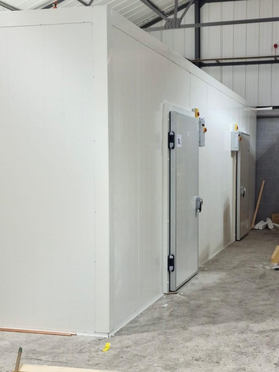 Modular cold room with insulated panels and hinged door in a warehouse – installed by DLG Shopfitting